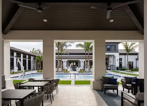 A patio with a table and chairs overlooking a pool.