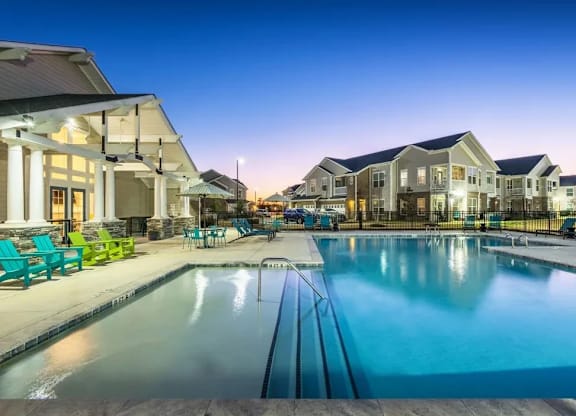 A swimming pool in front of a building with a sunset in the background.