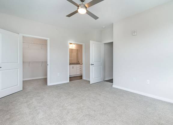 A room with a ceiling fan and carpeted floor.