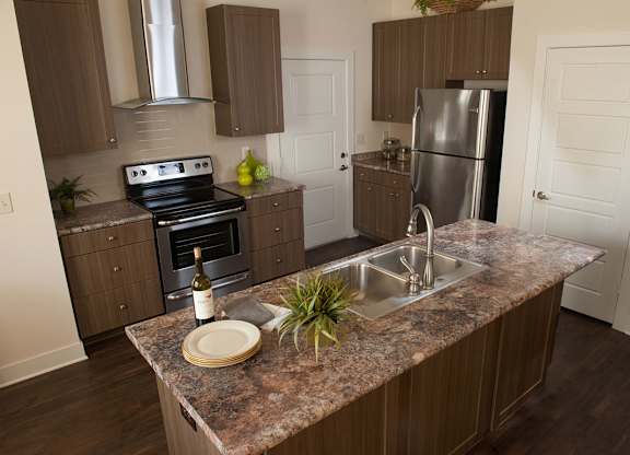 A kitchen with a granite countertop and a stainless steel refrigerator.