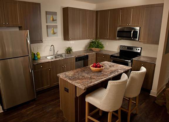 A kitchen with a granite countertop and stainless steel appliances.