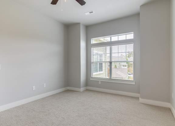A room with a window and a ceiling fan.
