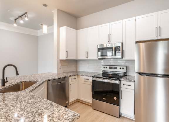 A kitchen with a granite countertop and stainless steel appliances.
