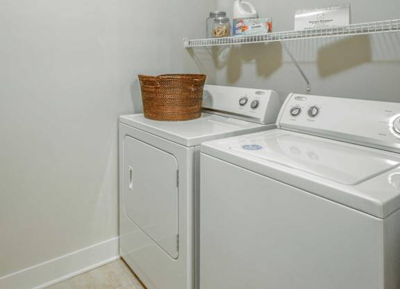 A white washing machine and dryer with a basket on top of the dryer.
