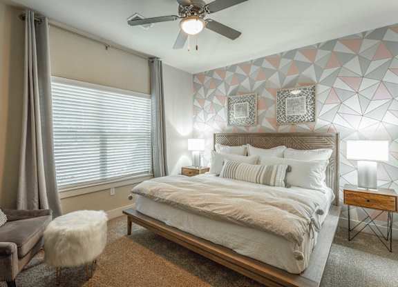 A bedroom with a bed, a chair, and a ceiling fan.
