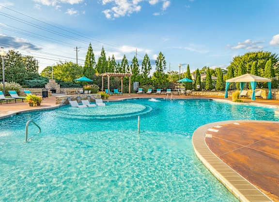 A large swimming pool with a wooden deck and lounge chairs.