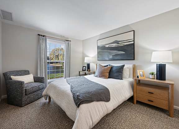 A bedroom with a large bed, a chair, and a painting on the wall.