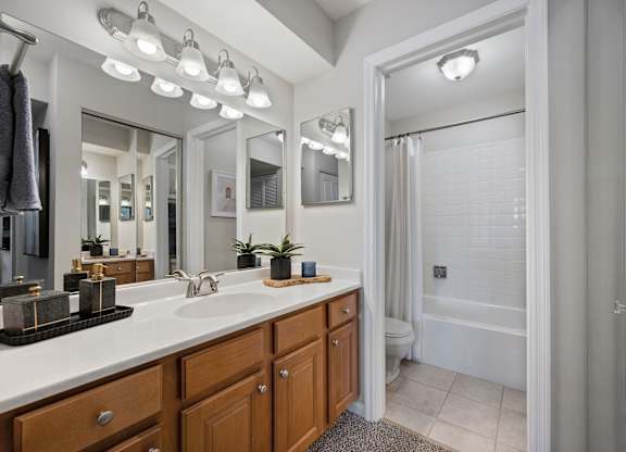 A bathroom with a white sink and brown drawers.