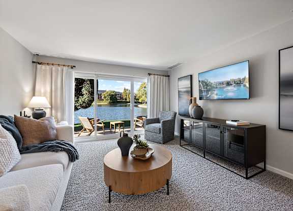 A living room with a large window overlooking a body of water.