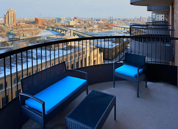 A balcony with a black railing has two chairs and a table.