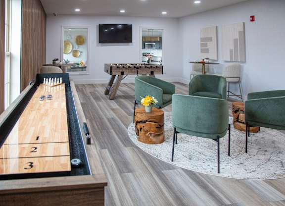 A pool table with numbered pockets is in the middle of a room with a green chair and a TV.