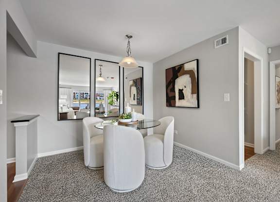 A modern living room with a glass table and white chairs.