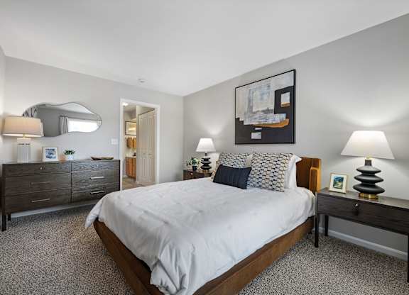 A bedroom with a large bed, a nightstand, and a dresser.