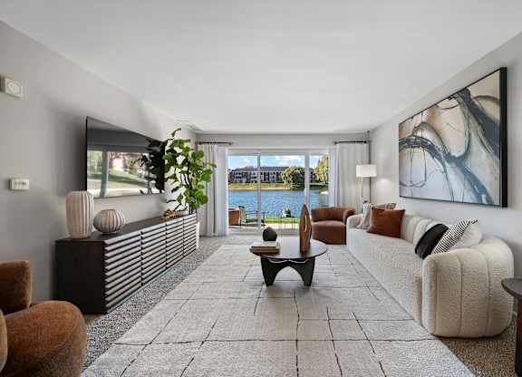 A spacious living room with a large window overlooking the water.