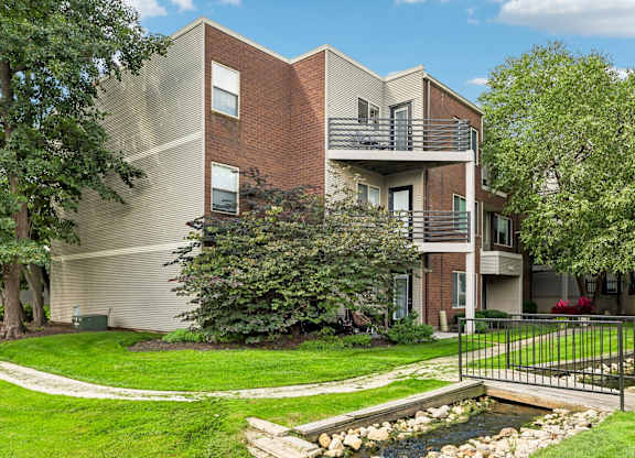 A modern apartment building with a small pond in front.