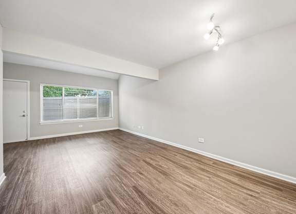 A room with wooden flooring and a window with blinds.