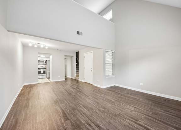 A large empty room with wooden flooring and white walls.