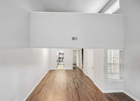 A long, empty hallway with a wooden floor and white walls.