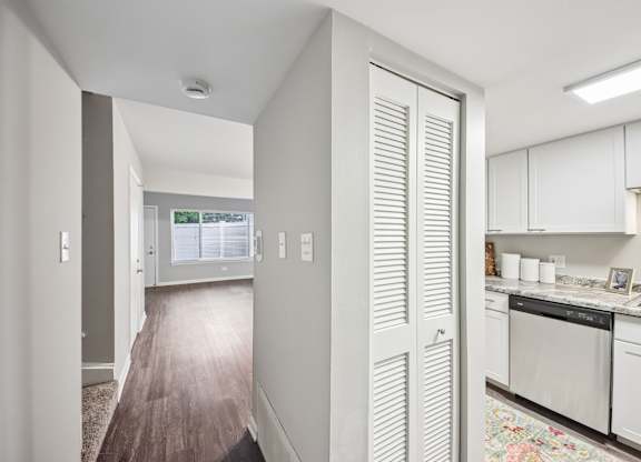 A kitchen with white cabinets and a wooden floor.