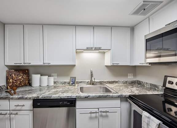 A kitchen with white cabinets and a granite countertop.
