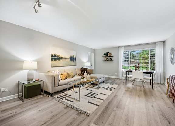 A living room with a white couch and a painting on the wall.