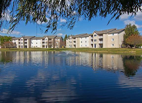 a fountain in the middle of a lake in front of an apartment building at Evergreen Luxury Apartments, Merrillville, 46410