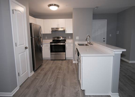 a kitchen with white cabinets and stainless steel appliances at Evergreen Luxury Apartments, Indiana