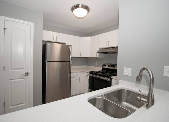 a kitchen with white cabinets and stainless steel appliances at Evergreen Luxury Apartments, Merrillville, Indiana