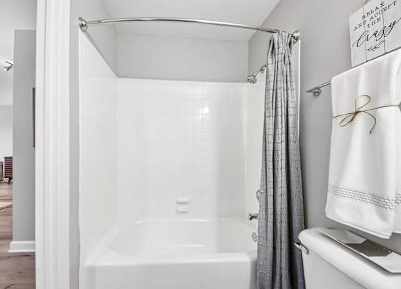 A white bathroom with a white tub and a white towel.