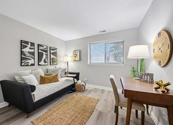 A living room with a couch, a table, and a clock on the wall.