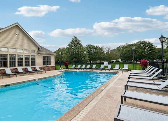 A pool with sun loungers and a building in the background.
