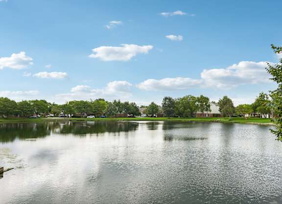 A serene lake surrounded by lush greenery under a clear blue sky.
