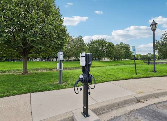 A black post with a white box on top is in the middle of a sidewalk.