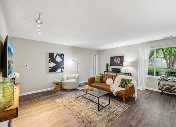 A living room with a brown couch and a glass coffee table.