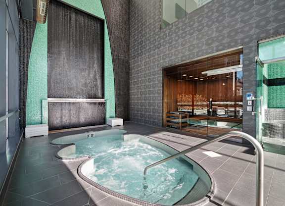 A hot tub sits in the middle of a room with a glass wall.