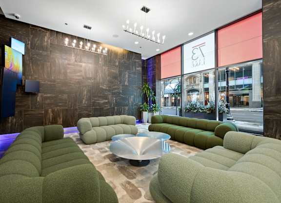 A modern waiting area with green couches and a wooden wall.