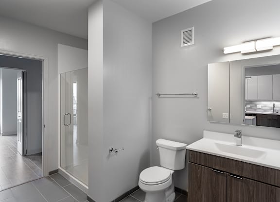 a bathroom with a toilet sink and mirror and a shower at Residences at Addison Clark Apartments, IL, 60613