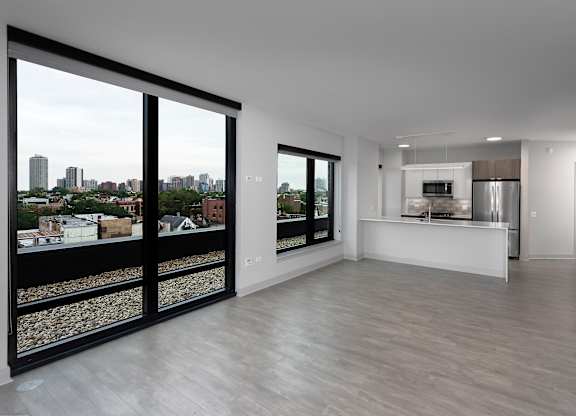 a living room and kitchen with large windows and a city view at Residences at Addison Clark Apartments, Chicago, 60613