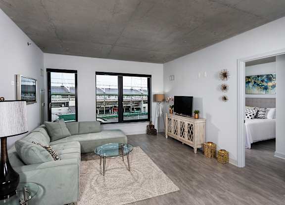 a living room with a gray couch and a glass coffee table and sliding glass doors at Residences at Addison Clark Apartments, Chicago, IL, 60613