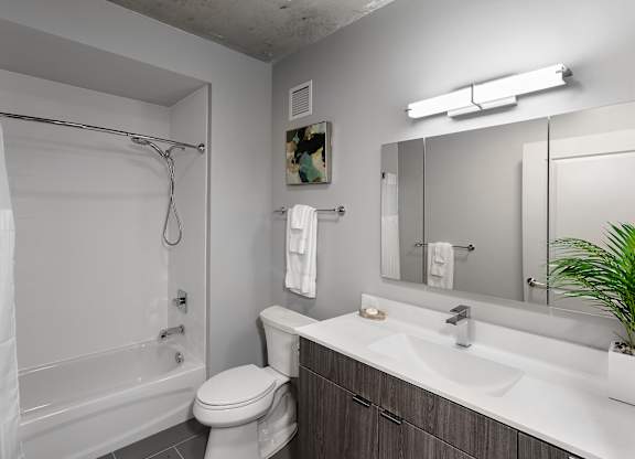 a bathroom with a shower toilet and sink and a mirror at Residences at Addison Clark Apartments, Chicago, IL, 60613