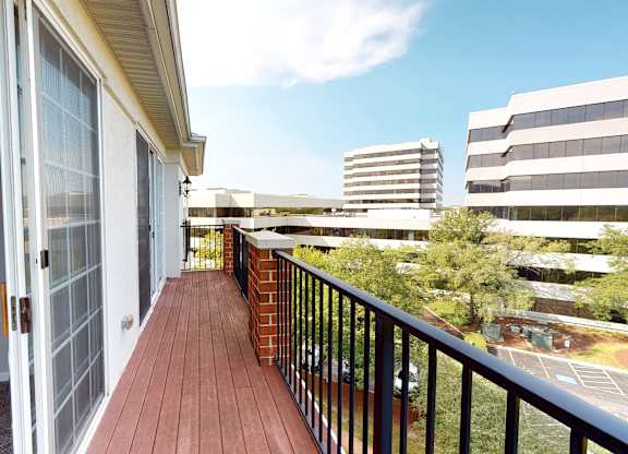 A balcony with a black railing and a brick pillar.