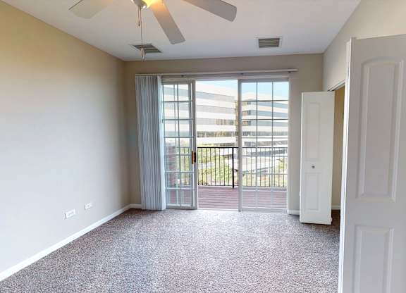 A room with a ceiling fan and a door leading to a balcony.