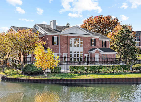 A house with a red brick exterior sits next to a body of water.