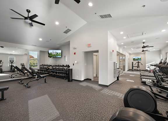A gym with a variety of equipment including treadmills, weights, and exercise bikes.