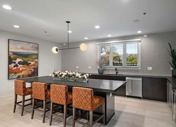 A modern kitchen with a large island and chairs.