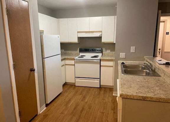 A kitchen with white appliances and wooden floors.