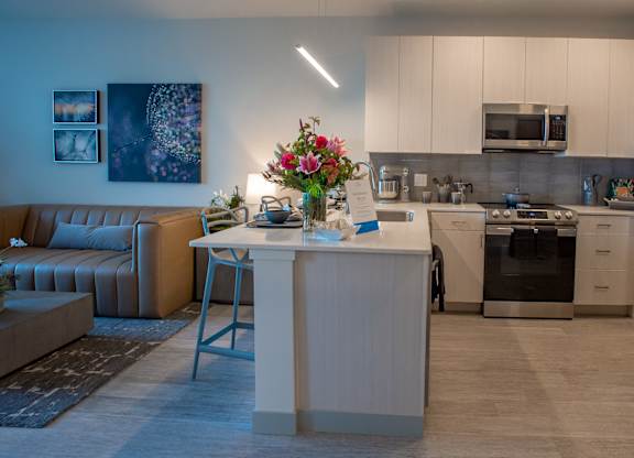 a living room with a kitchen and a table with flowers at 42 Hundred On The Lake, St Francis, WI, 53235