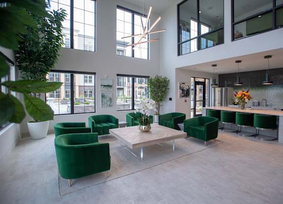 the lobby of a building with green chairs and a table at 42 Hundred On The Lake, St Francis, WI