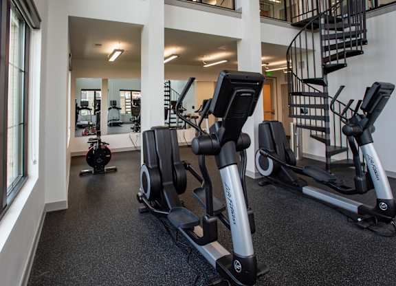 a gym with cardio equipment and a spiral staircase at 42 Hundred On The Lake, St Francis, WI