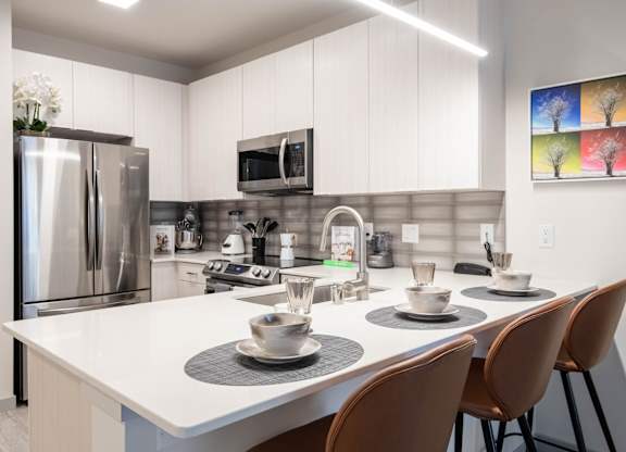 A modern kitchen with a white table and chairs. at Elevate Apartments, Madison, 53718